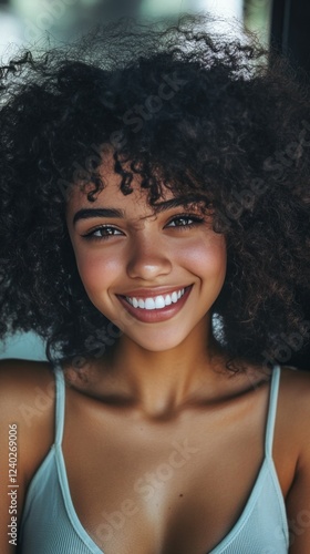Bright smile of a young woman with curly hair indoors during daytime