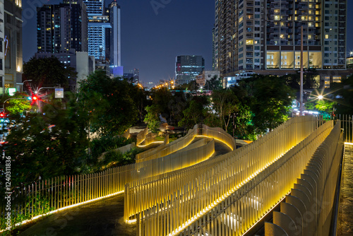 View of the empty and illuminated Chong Nonsi Canal Park and tall skyscrapers in Khlong Chong Nonsi district in Bangkok, Thailand at dusk. photo