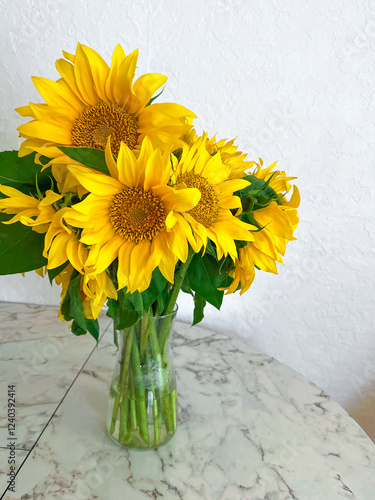 Obraz na płótnie A bouquet of sunflowers stands in a glass vase on a marble table in a white kitchen w salonie