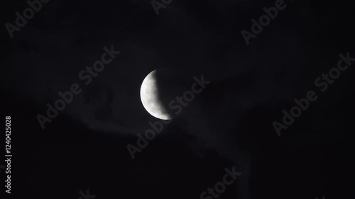Lunar eclipse view over the dark sky with clouds partially covering the moon