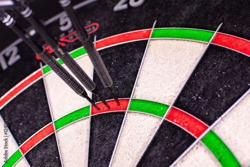 Official dartboard with closeup view of three darts sticking in the Triple 20