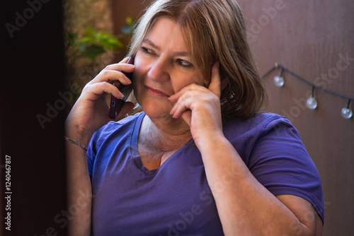 Mature woman thinking with mobile phone on the terrace of her house photo