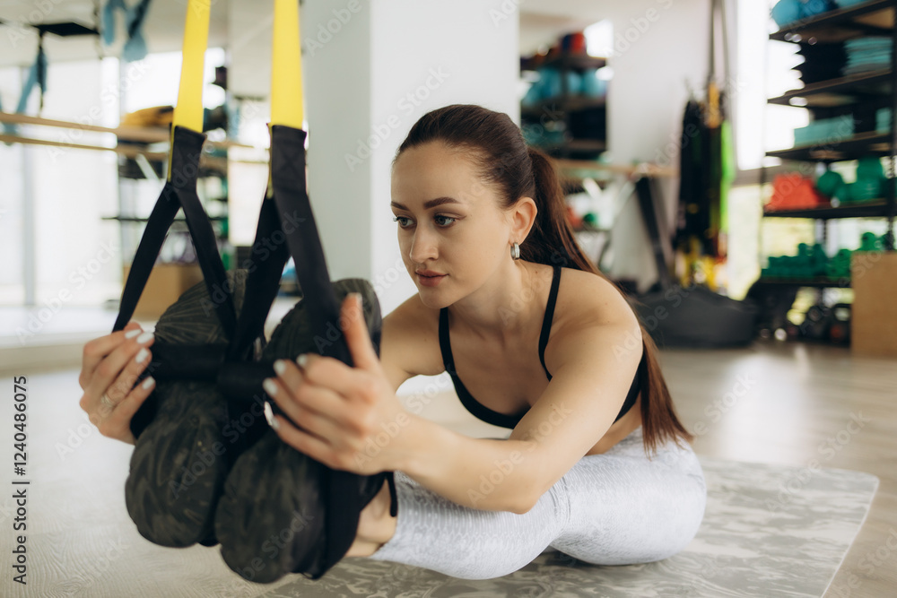Woman Practicing Stretching Exercises Using Suspension Straps in a Gym Setting Woman Practicing Stretching Exercises Using Suspension Straps in a Gym Setting