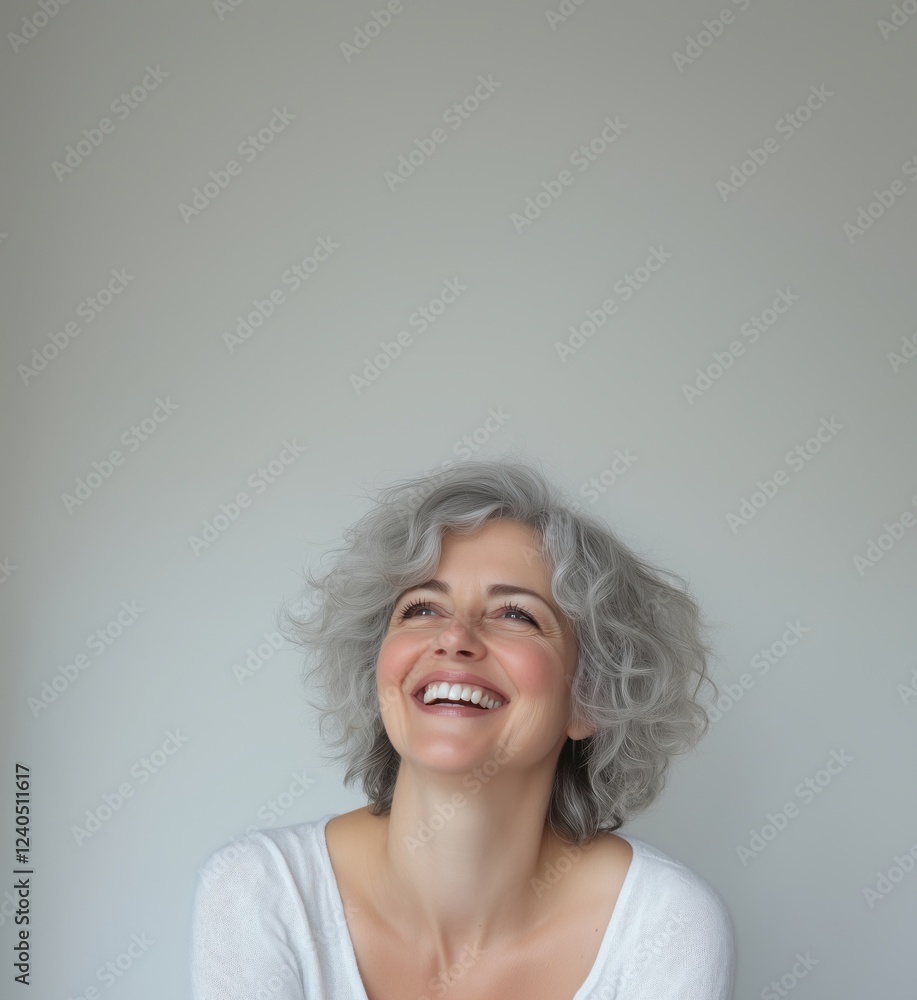 Smiling woman with gray curly hair expressing joy and happiness against a neutral background, showcasing natural beauty and confidence, copy space for text Smiling woman with gray curly hair expressing joy and happiness against a neutral background, showcasing natural beauty and confidence, copy space for text