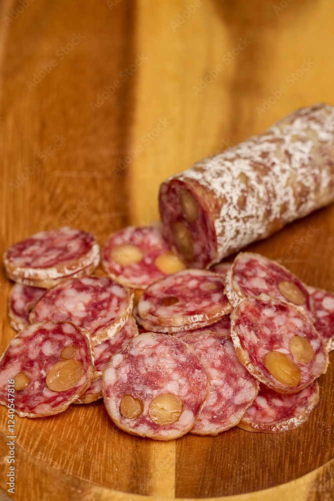 slices of fuet salami with walnuts on a wooden chopping board slices of fuet salami with walnuts on a wooden chopping board