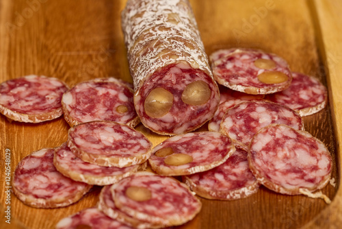 slices of fuet salami with walnuts on a wooden chopping board photo