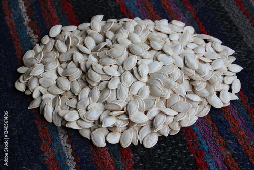Heap of pumpkin seeds on an old carpet.