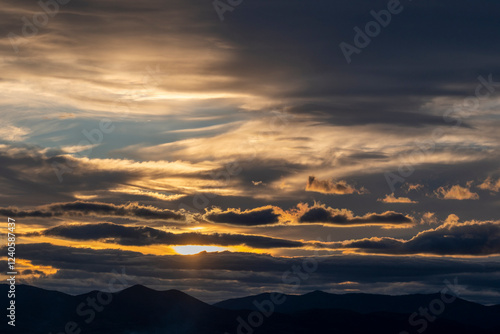 A visually striking image of dramatic clouds painted in warm earth tones during sunset, symbolizing tranquility and the breathtaking beauty of nature's transitions. photo