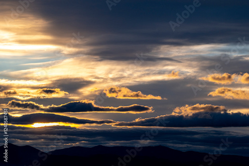 An impressive sunset scene showcasing a stunning sky with silhouetted mountains, blending colors and shadows to create a dramatic and picturesque vista. photo