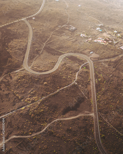Aerial view of volcanic terrain with buried houses and a curved road, Los Llanos de Aridane, Spain.