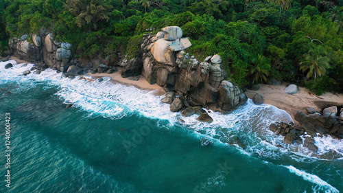 Aerial view of Tayrona beach surrounded by lush jungle and rocky coastline with waves crashing into the ocean, Santa Marta, Colombia. photo