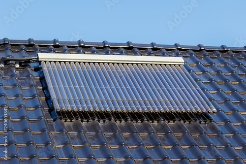 Schilderij op canvas Solar thermal collector with vacuum tubes is mounted on a glossy black tiled roof under a clear blue sky