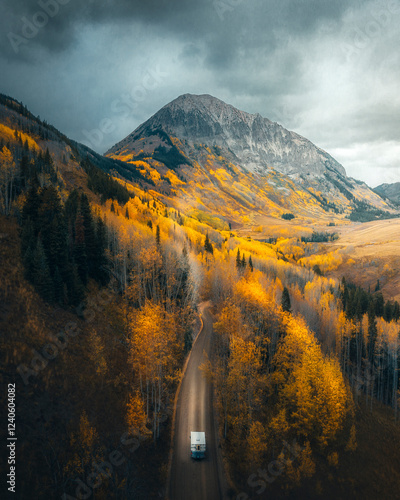 Aerial view of vibrant autumn foliage with a campervan on a scenic road surrounded by majestic mountains and tranquil forests, Crested Butte, United States. photo