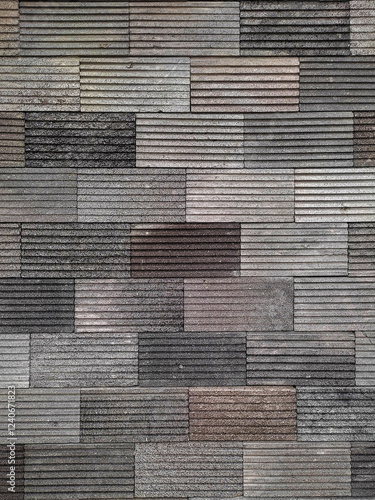 This image shows a textured brick wall with rectangular gray blocks arranged in a structured pattern. The horizontal grooves add depth and a modern architectural style.
