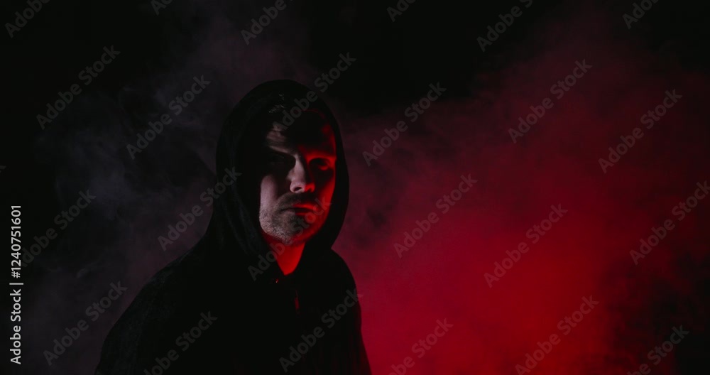 Dark hooded Man in dramatic red light and fog Dark hooded Man in dramatic red light and fog