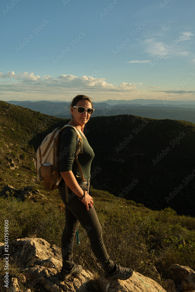 Naklejka premium Woman with a backpack on her back on top of a mountain
