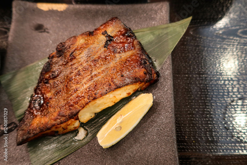 close up of Japanese grilled Saikyo miso Snow black cod Fish on a leaf and serving plate photo