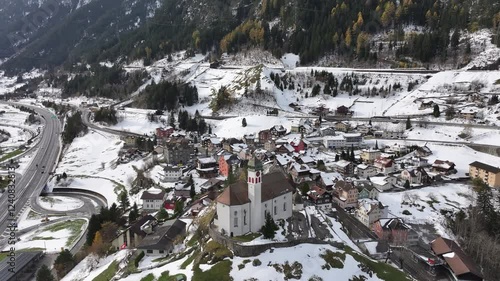 Aerial view of wassen church surrounded by a beautiful snowy village and towering mountains, canton uri, Switzerland. photo