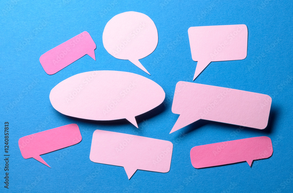 Pink blank cut out paper speech bubbles with copy space for text on blue background, flat lay top view discussion conversation concept Pink blank cut out paper speech bubbles with copy space for text on blue background, flat lay top view discussion conversation concept