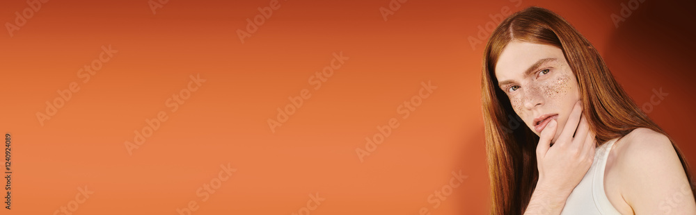 Stylish queer man poses against a vibrant orange wall showcasing modern youth fashion Stylish queer man poses against a vibrant orange wall showcasing modern youth fashion