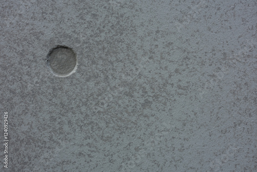 Φωτογραφία A textured grey surface features a single, round indentation on the left