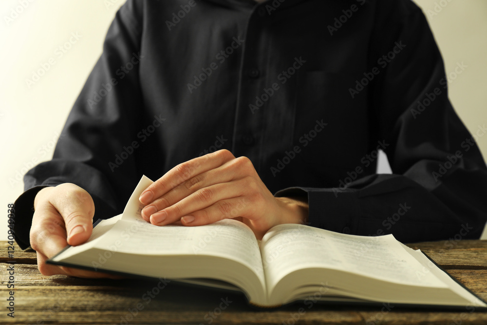 Woman reading Holy Bible in English language at wooden table, closeup Woman reading Holy Bible in English language at wooden table, closeup