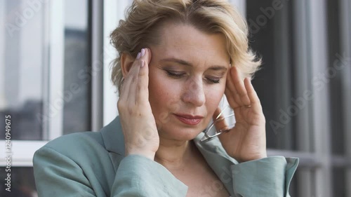 Unhappy senior adult ill woman rubbing temple feeling headache, suffering migraine