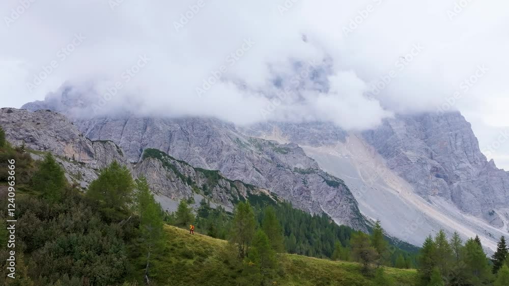 Aerial view of col de la puina with a person hiking among majestic mountains and serene clouds, Borca di Cadore, Italy. Aerial view of col de la puina with a person hiking among majestic mountains and serene clouds, Borca di Cadore, Italy.