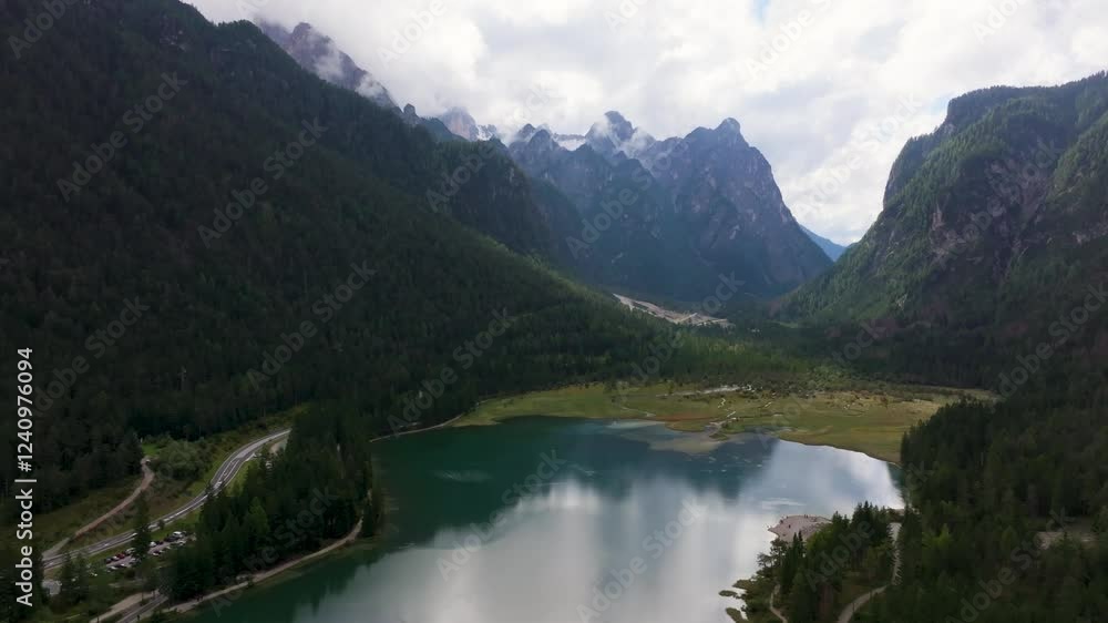 Aerial view of serene Dobbiaco Lake surrounded by majestic mountains and lush forest, Toblach, Italy. Aerial view of serene Dobbiaco Lake surrounded by majestic mountains and lush forest, Toblach, Italy.