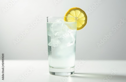 a glass of ice water with a slice of lemon on white background photo