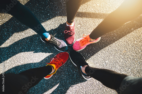 Fotografía Runner, shoes and group in circle, friends and above for direction, training or connection on asphalt