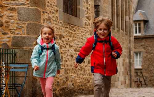 Children travelers joyfully run on a historic cobblestone path photo