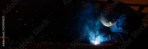A man in a blue jacket is welding long horizontal photo