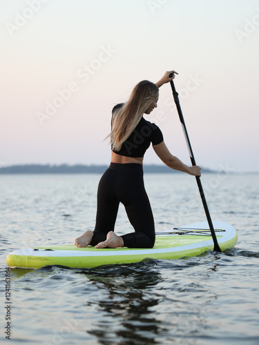 young woman on sapa riding on the water with paddle in hand. Summer swimming on a sap board. photo