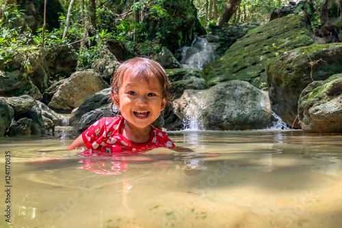 little asian girl playing by the waterfall with a heart full of laughter.