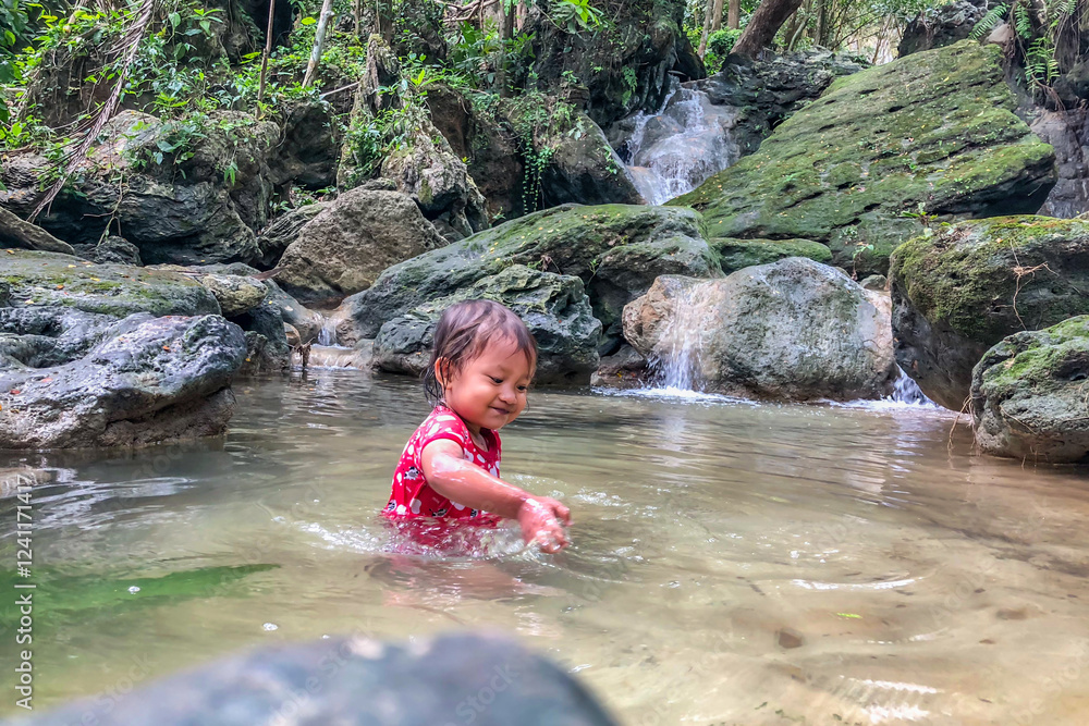 little asian girl playing by the waterfall with a heart full of laughter.