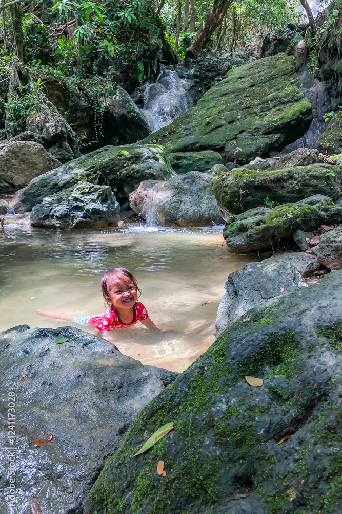 little asian girl playing by the waterfall with a heart full of laughter.