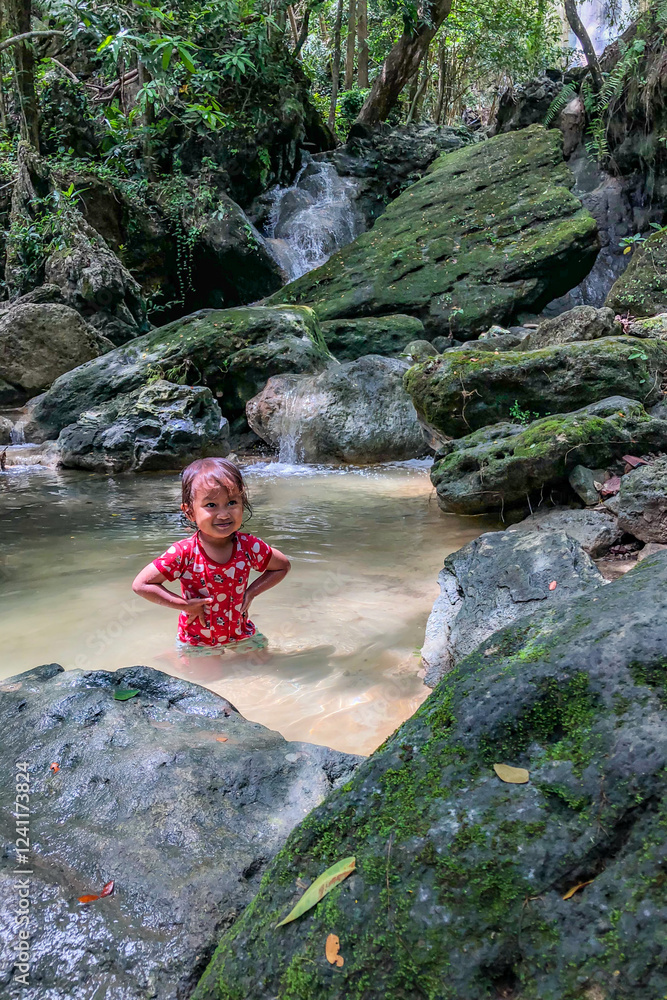 little asian girl playing by the waterfall with a heart full of laughter.