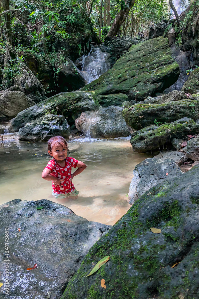 little asian girl playing by the waterfall with a heart full of laughter.