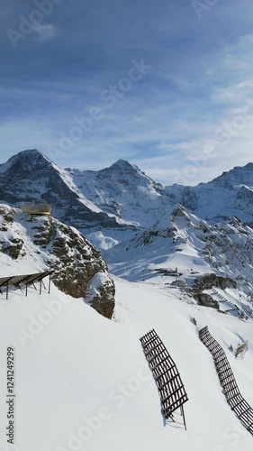 Eiger North Face, Monch and Jungfrau Mountains in Winter. Swiss Alps. Switzerland. Aerial View. Moving Forward and Upwards over Mannlichen Top. Reveal Shot. Anti-Avalanche Structures. Vertical Video