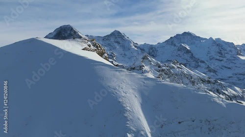 Eiger North Face, Monch and Jungfrau Mountains in Winter. Swiss Alps. Switzerland. Aerial View. Moving Forward and Upwards over Snowy Mannlichen Top. Reveal Shot. Anti-Avalanche Structure, Barrier