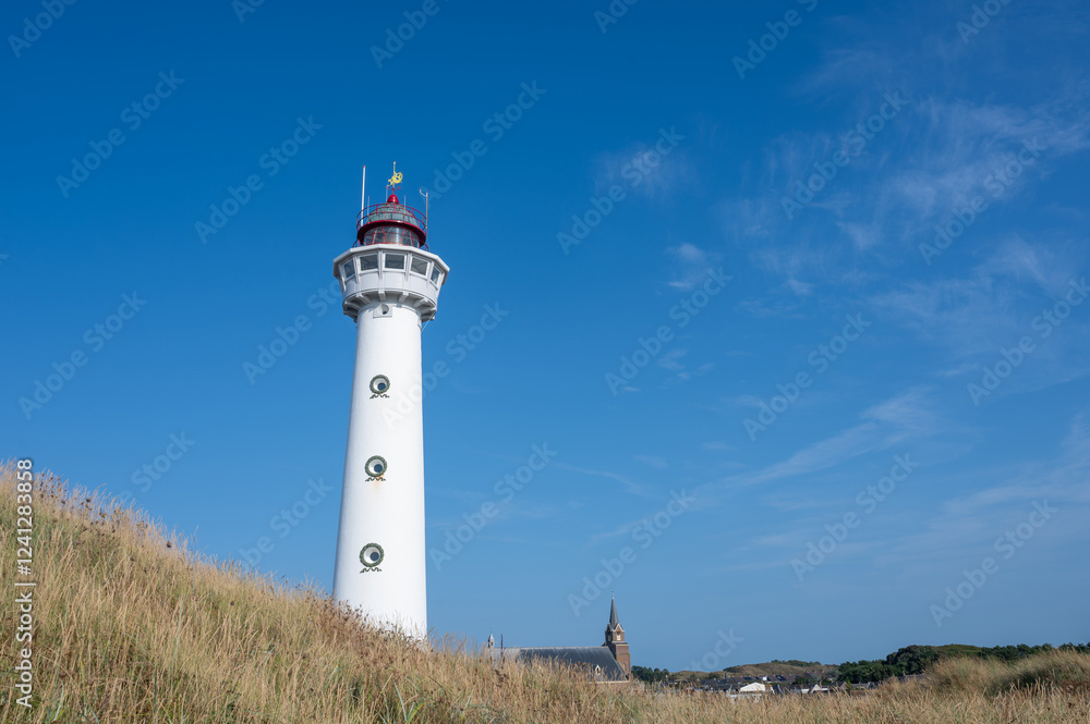 Lighthouse in the Dutch town of Egmond aan Zee with a church and sand dune Lighthouse in the Dutch town of Egmond aan Zee with a church and sand dune