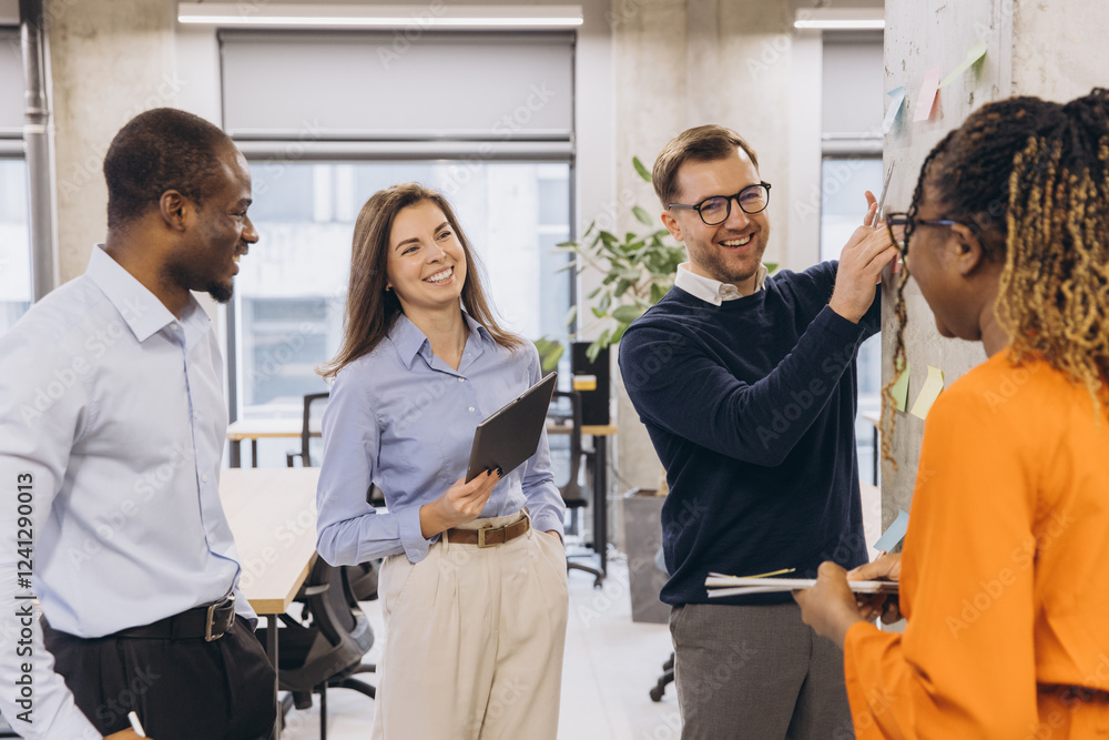 Business colleagues discussing work using sticky notes on a wall, showcasing teamwork and collaboration in a modern office environment