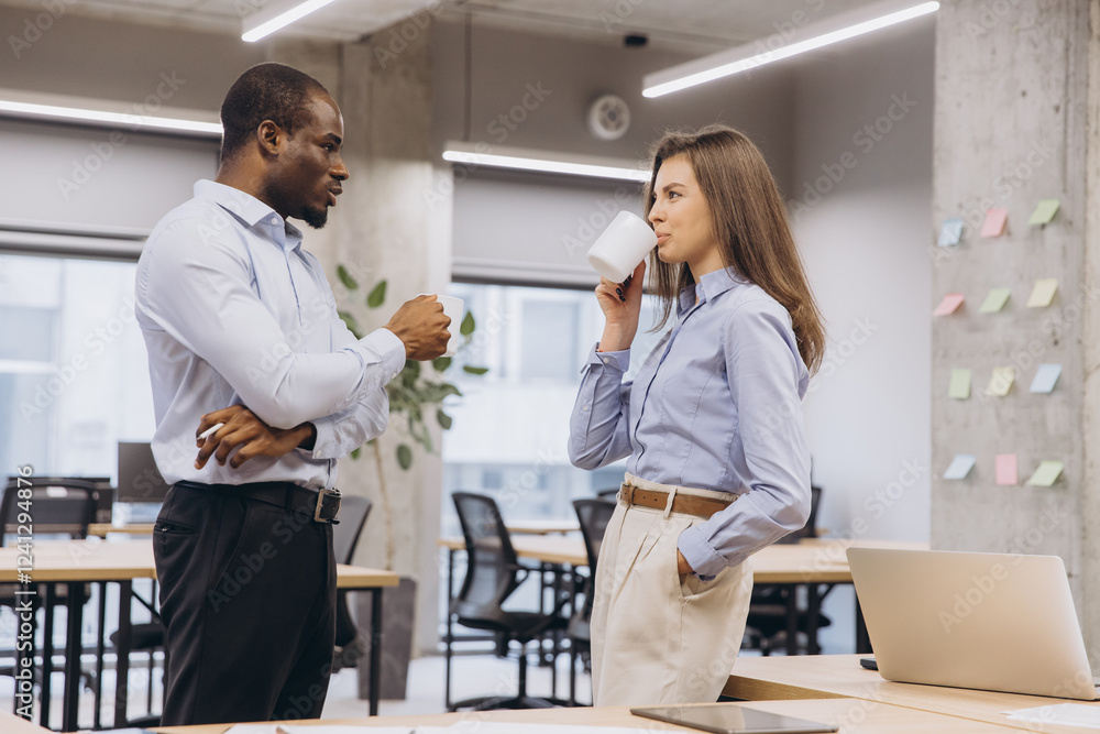 Fototapeta premium Multi ethnic colleagues enjoying a coffee break, chatting and relaxing in a modern office environment