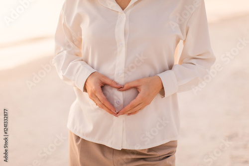 woman making a heart on her pregnant belly 