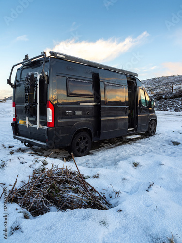 Black campervan overnight parking besides a snowy road on the Isle of Skye after a night of snow