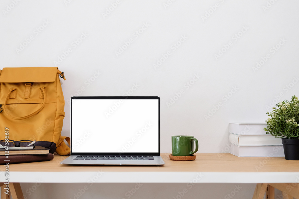 Front view of work desk with yellow bag leaning against wall and laptop with blank screen. Front view of work desk with yellow bag leaning against wall and laptop with blank screen.