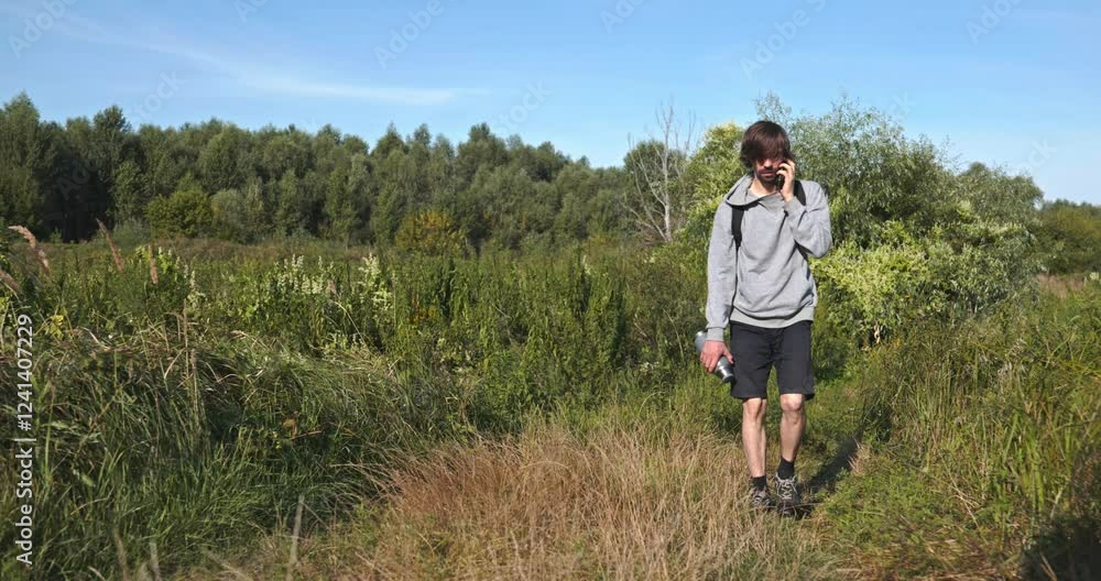 Caucasian Man Walks With Smartphone Near River. Hiking on Nature. Slow motion 60fps 4K 10-bit Caucasian Man Walks With Smartphone Near River. Hiking on Nature. Slow motion 60fps 4K 10-bit