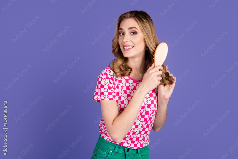 A stylish woman brushing her hair in casual attire against a vibrant purple background A stylish woman brushing her hair in casual attire against a vibrant purple background