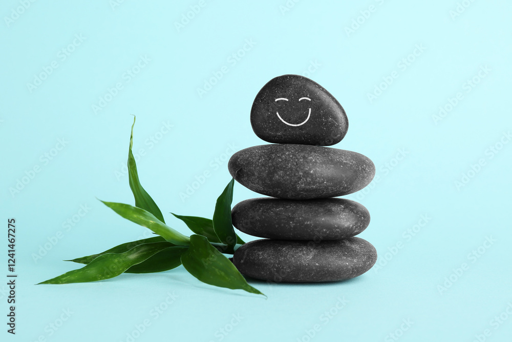 Stack of rocks with drawn smiley face on light blue background. Harmony and life balance Stack of rocks with drawn smiley face on light blue background. Harmony and life balance